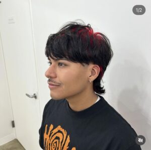 Men's black mullet with vivid red shadow roots, showing a "glow" color effect at the scalp, styled at Assort Osaka.
