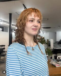 Side profile of a Ragtail cut, highlighting the balance of crown volume and elongated nape for textured hair.